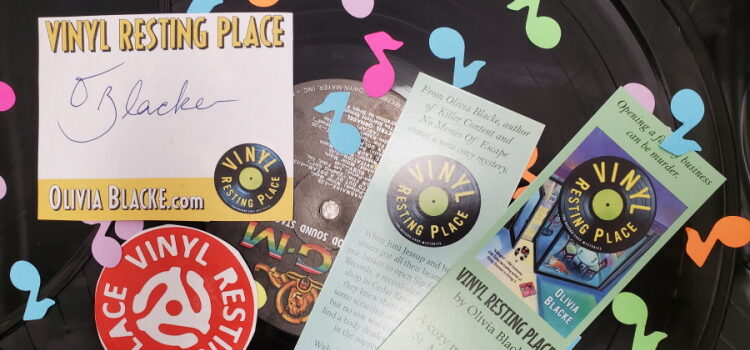 Vinyl Resting Place bookplate, bookmarks, and sticker along with musical-note shaped confetti on top of a vinyl record